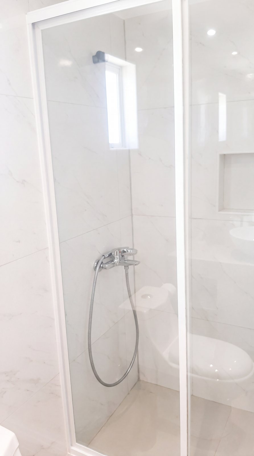 Mampara de ducha de vidrio con perfil de aluminio blanco, obra de INGEALUM