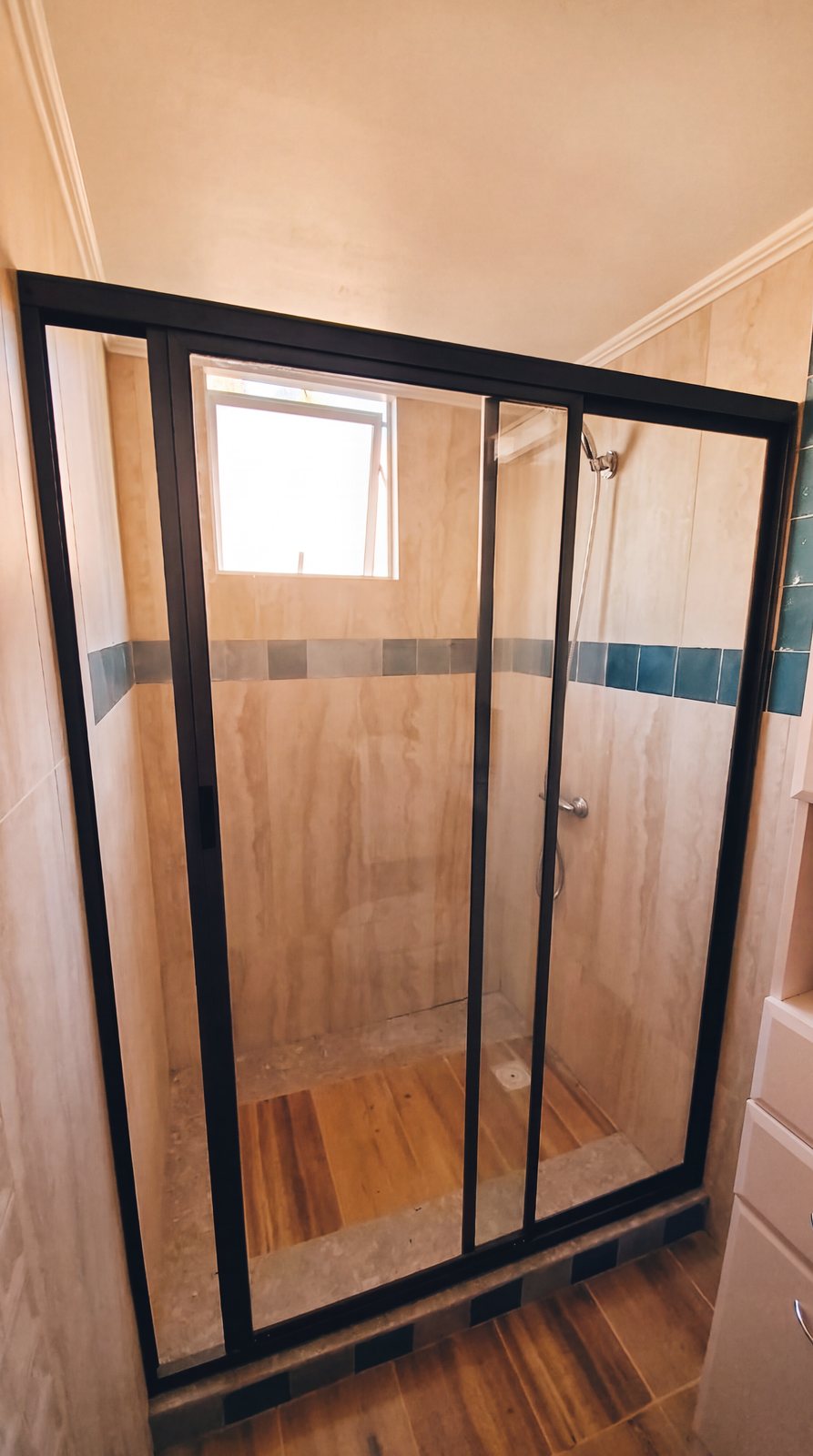 Mampara de ducha con perfil de aluminio negro en baño revestido en madera, obra de INGEALUM