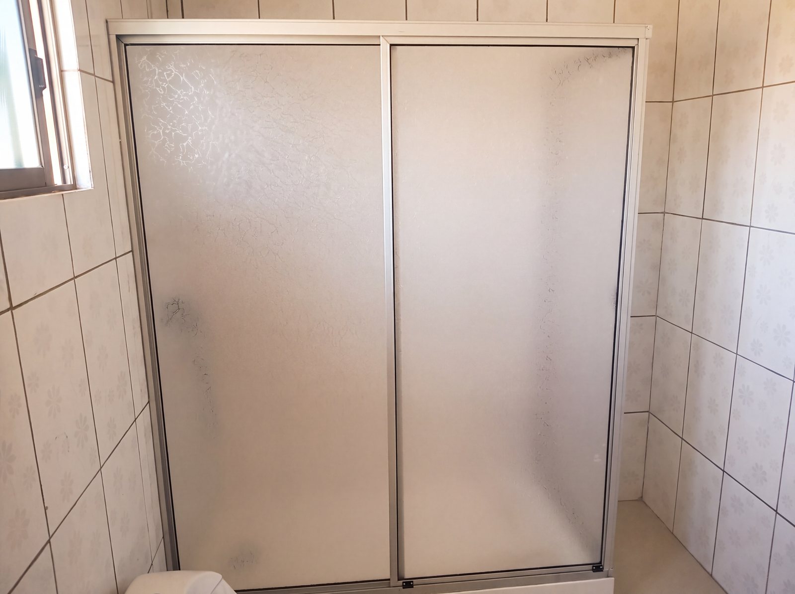 Mampara de ducha de vidrio pavonado con puerta corredera, obra de INGEALUM