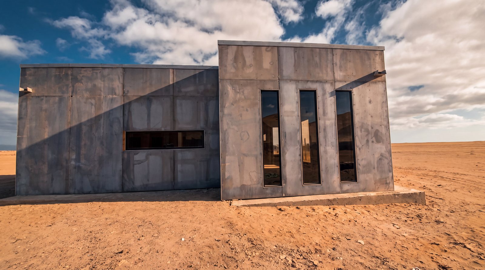 Nave de hormigón con ventanas verticales de aluminio en el desierto, obra de INGEALUM